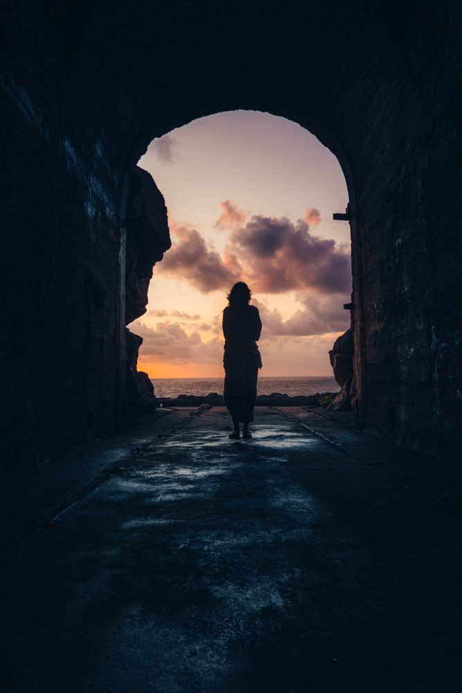 Silhouette of person walking in tunnel