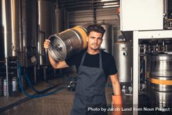 Craft brewer working in keg storage room with metal tanks in background 5oA3kb
