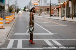 Woman standing in the crosswalk wearing red heels holding a newspaper 5nMY20