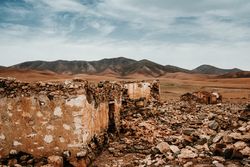 Dilapidated old buildings in mountain desert under cloudy sky