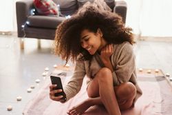 Black woman taking selfie on floor