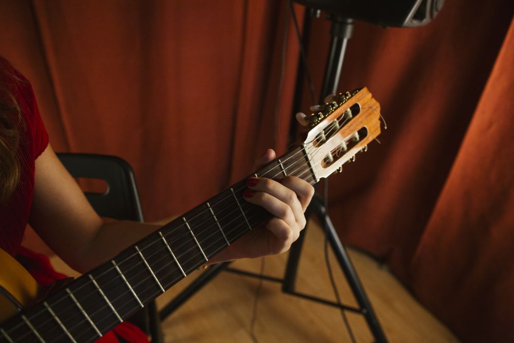 Crop woman playing guitar on stage