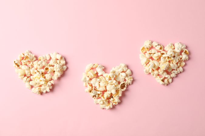Flat lay composition with popcorn hearts on pink background, space for text
