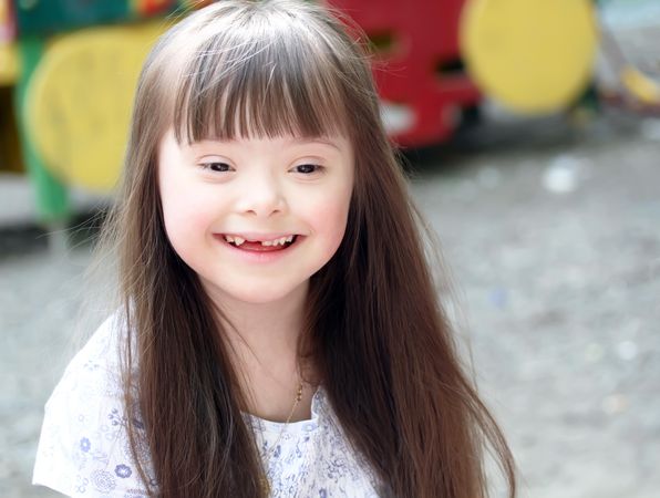 Portrait of a young girl with Down syndrome with long straight brown hair
