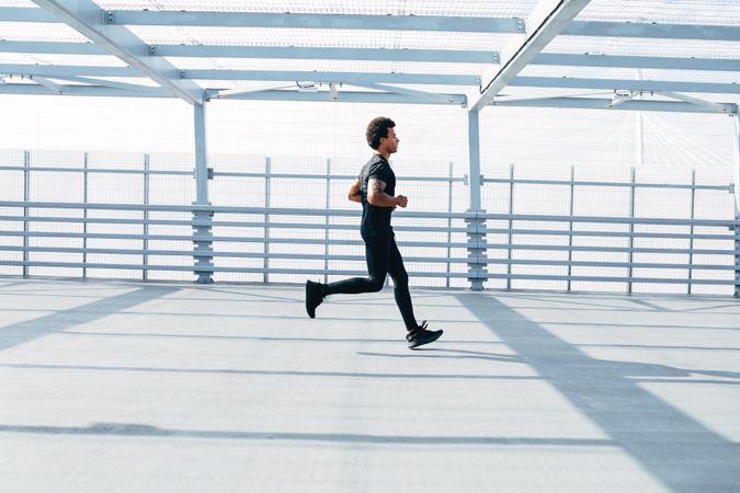Man running on bridge in dark clothes