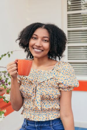 Young woman sitting drinking coffee on the terrace of a house