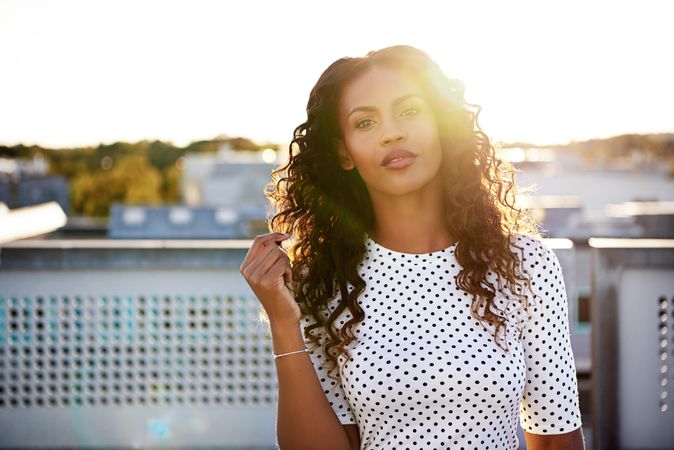 Radiant Black woman in spotted shirt on roof top