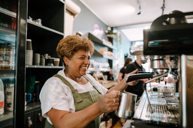 Older Black woman preparing coffee in cafe