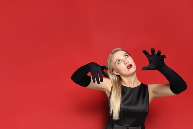 A young woman in a zombie costume, on the occasion of the Halloween holiday, on a red background.