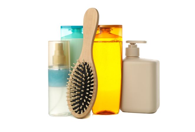 Blank cosmetics bottles and hair brush isolated on light background