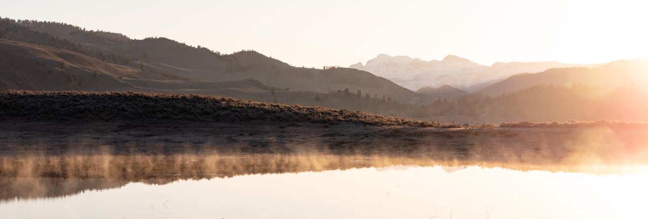 Wide shot of sunrise over steam from ponds in Yellowstone National Park, USA