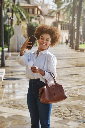 Positive Black female taking selfie on street