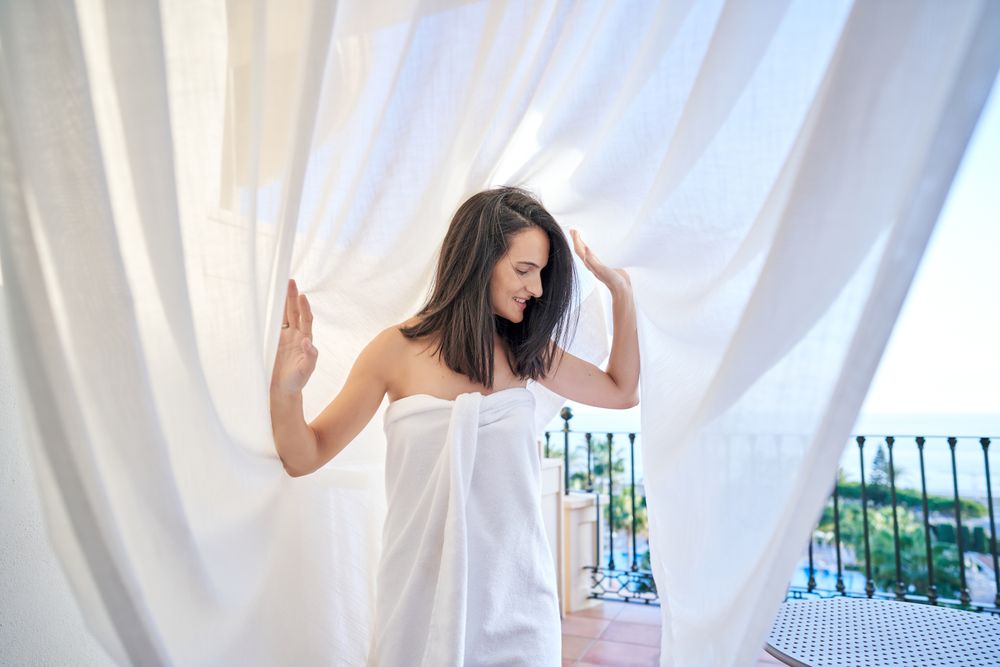 Hispanic woman under white tulle on terrace