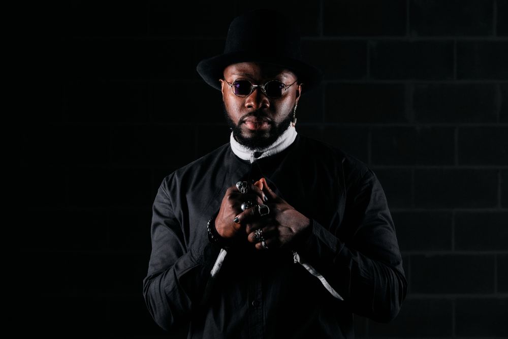 Stylish Black man looking at camera in black studio