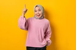 Smiling Muslim woman smiling and pointing upwards with good idea
