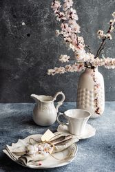 Top view of spring floral concept with apricot blossom in modern vase on grey room with tea cups
