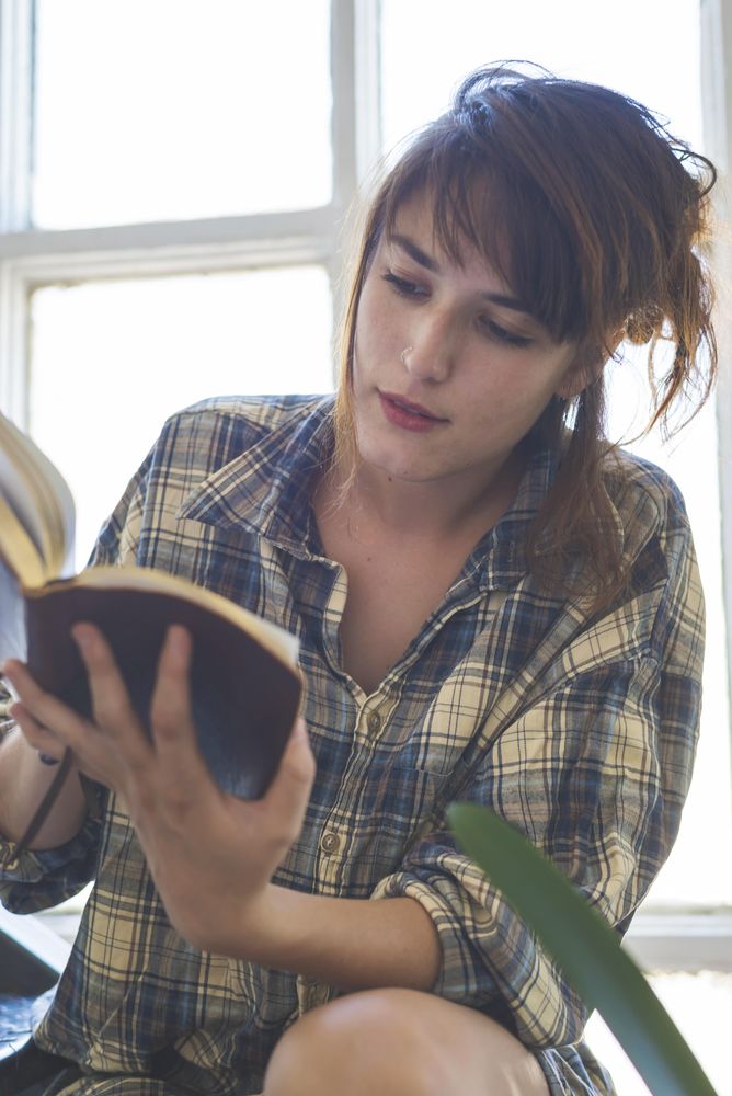 Female reading book on stairs in bright room
