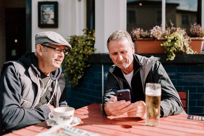 Two men looking at phone at outdoor pub