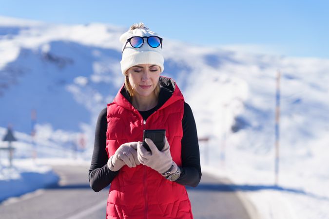 Woman in wintry gear checking phone on cold day