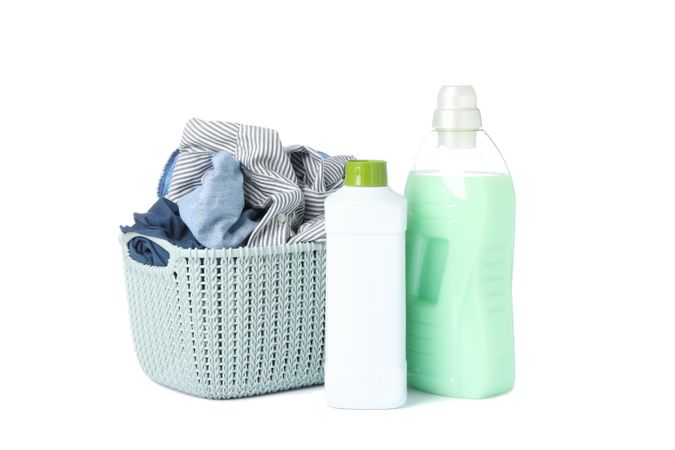Laundry detergent and basket with clothes isolated on blank background