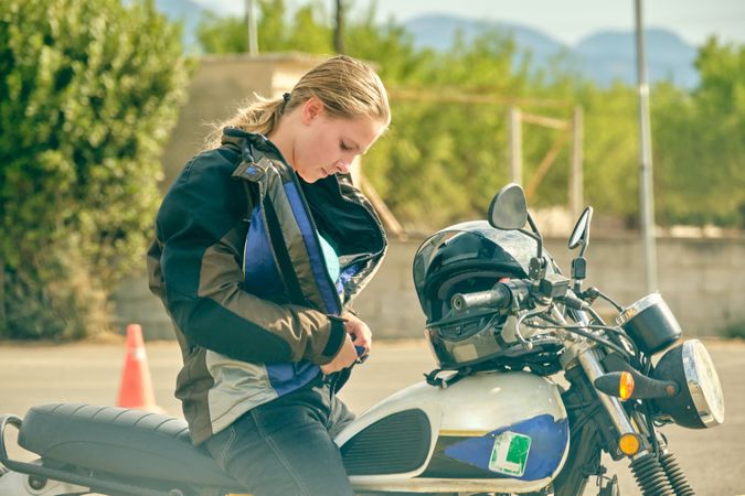 Woman sitting on motorbike and putting on jacket
