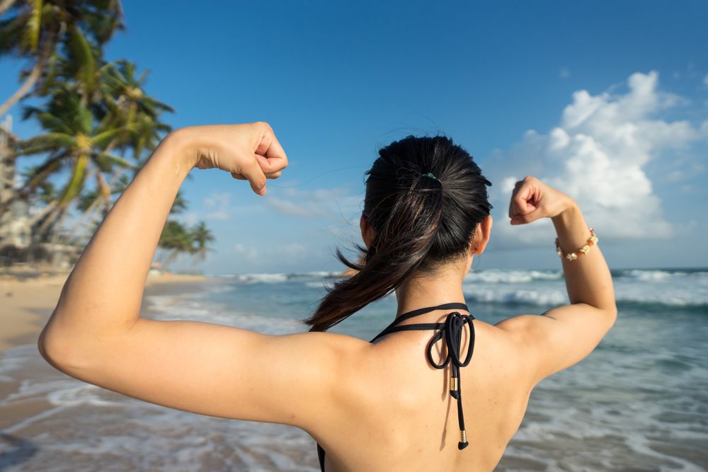 Young woman in water on sand beach with tropical forest