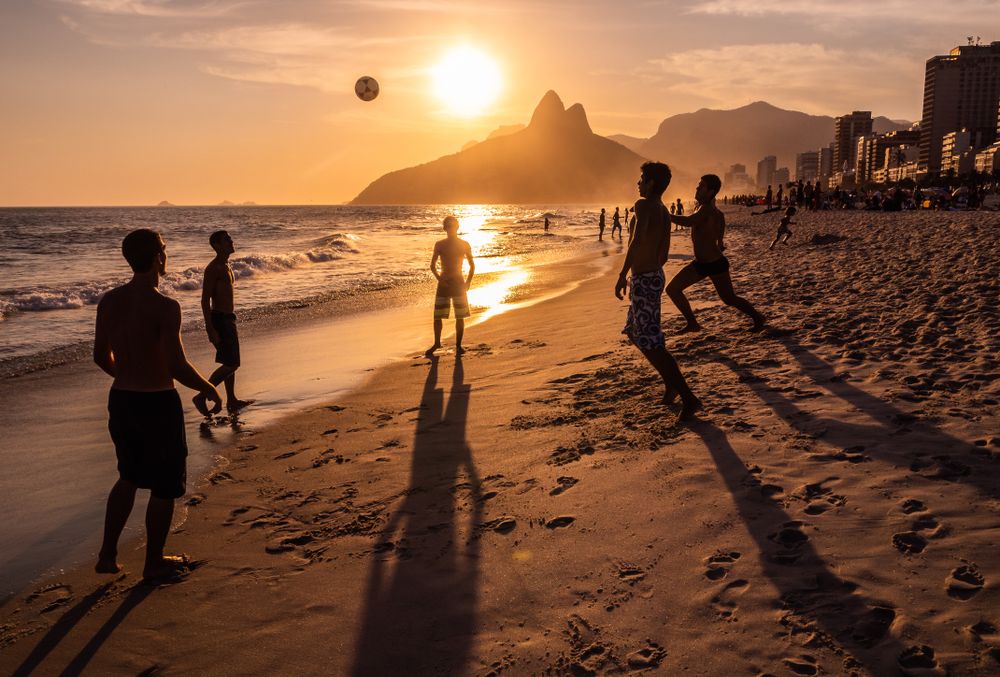 Rio de Janeiro, Brazil - February 13 2014: Young men throwing ball on beach during sunset