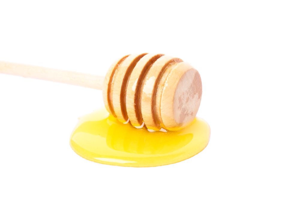 Dipper and honey isolated on neutral background, close up