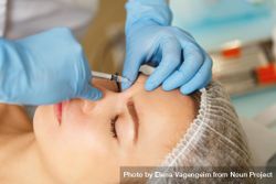 Cosmetologist at med spa injecting botox into forehead wrinkles in female client 4A2Vqb