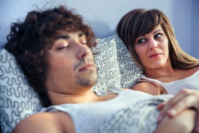 Frustrated woman looking at young man sleeping