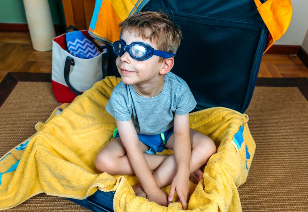 Funny boy smiling sitting inside a suitcase