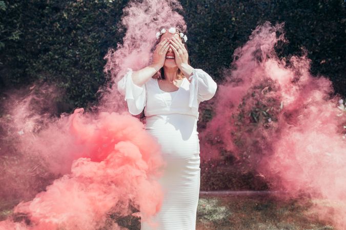 Pregnant woman outdoors with smoke grenade