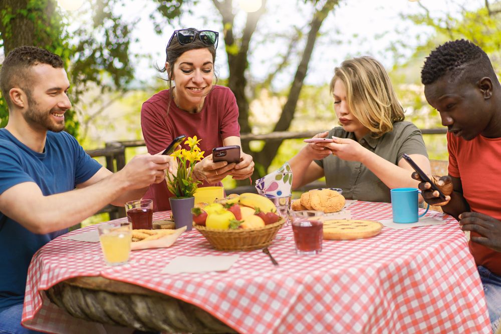 Two women enjoy capturing their vibrant brunch setup on smartphones