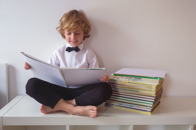 Cheerful boy reading book on table