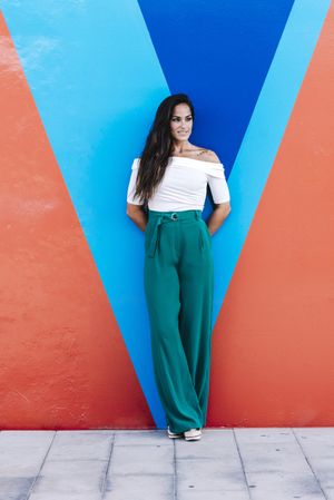 Elegant young woman leaning against a wall looking away
