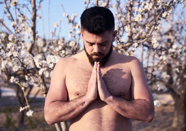 Shirtless man meditating in spring garden