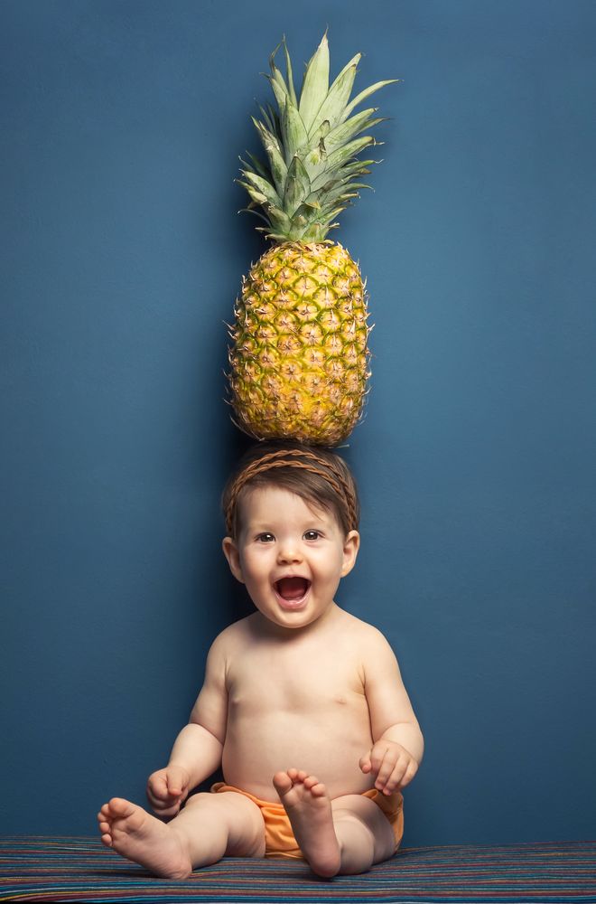 Happy baby holding a pineapple over her head