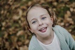 Smiling girl between meadow with dry leaves