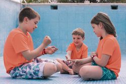 Children playing rock-paper-scissors in empty pool