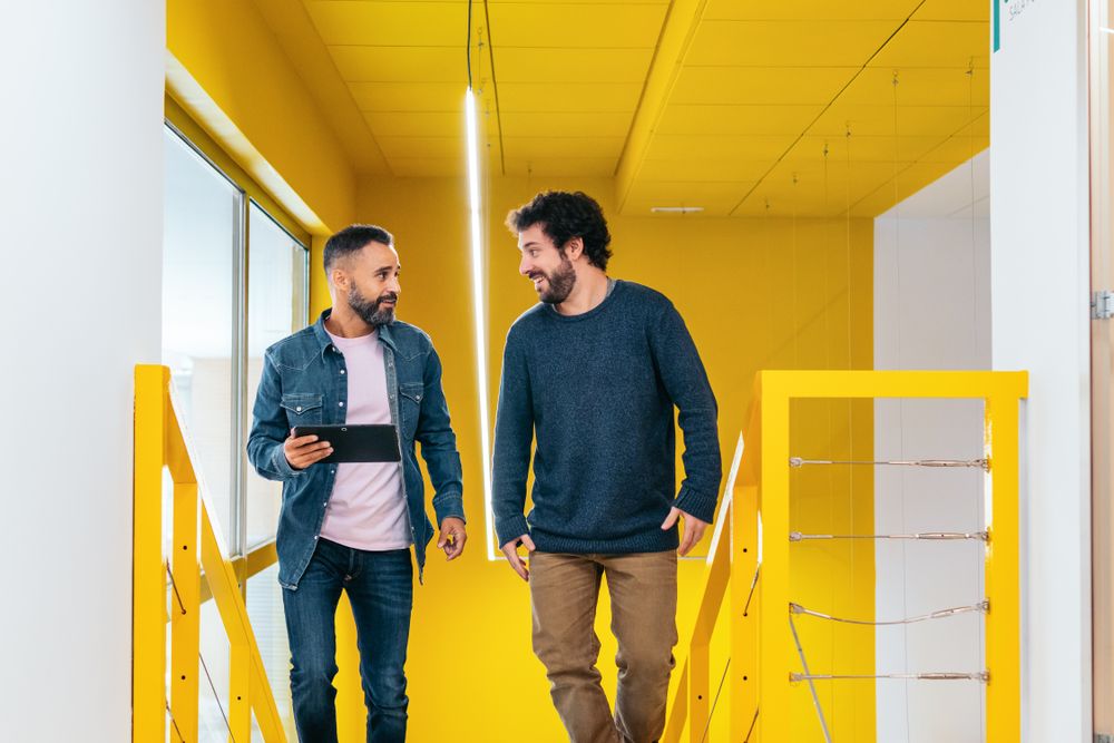Two male coworkers working and talking in a coworking