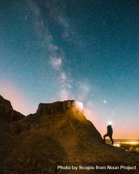 Silhouette of person standing on brown rock formation during nighttime bxMZa0