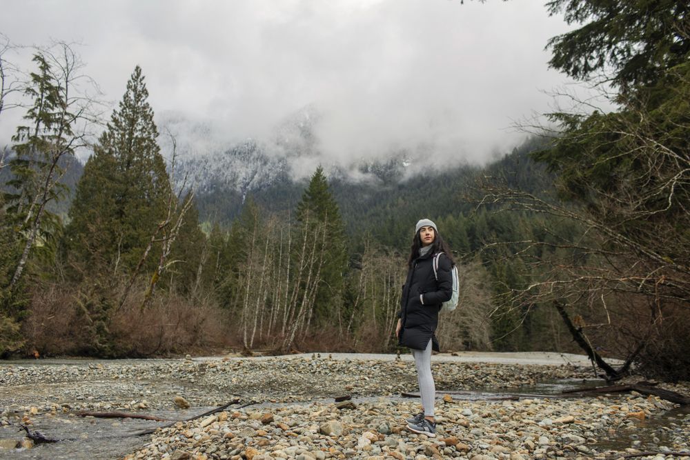 Young woman in the mountains standing near a stream