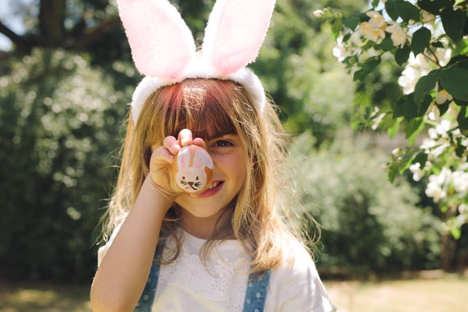 Close up of a smiling girl holding a painted easter egg in front of her face