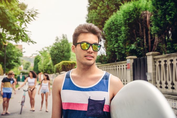 Close up of young man with sunglasses holding surfboard