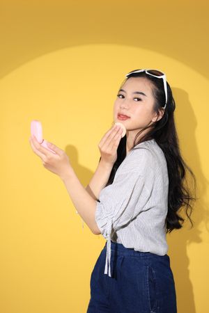 Stylish Young Asian Female Touch Up her Make Up using Pink Case Make Up Cushion