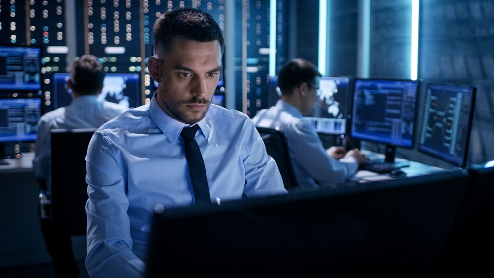Close-up of Technical Engineer Working on His Computer With Multiple Displays in Monitoring Room.