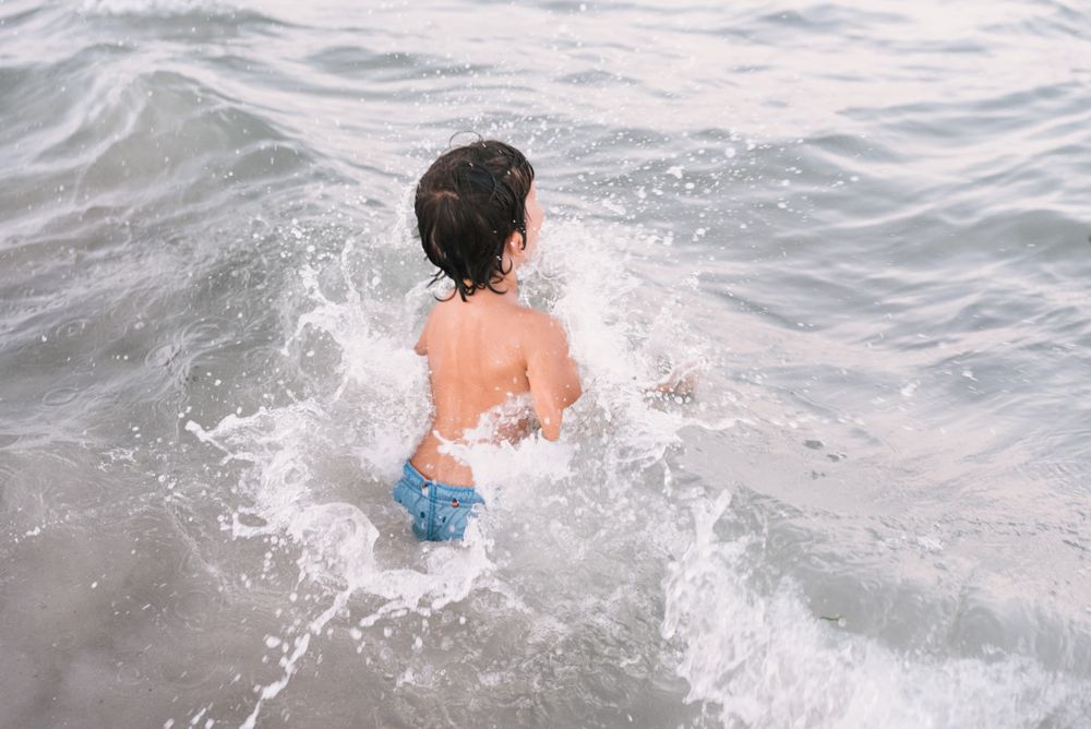 Boy walking in blue water of resort sea