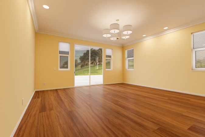 Newly Remodeled Room of House with Finished Wood Floors, Moulding, Light Yellow Paint and Ceiling Lights.
