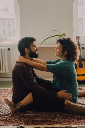 Loving couple embracing while sitting on apartment floor