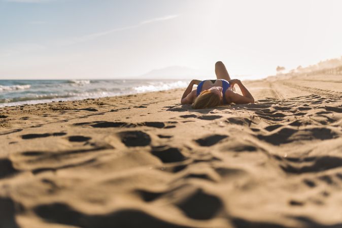 Woman lying down on sandy beach